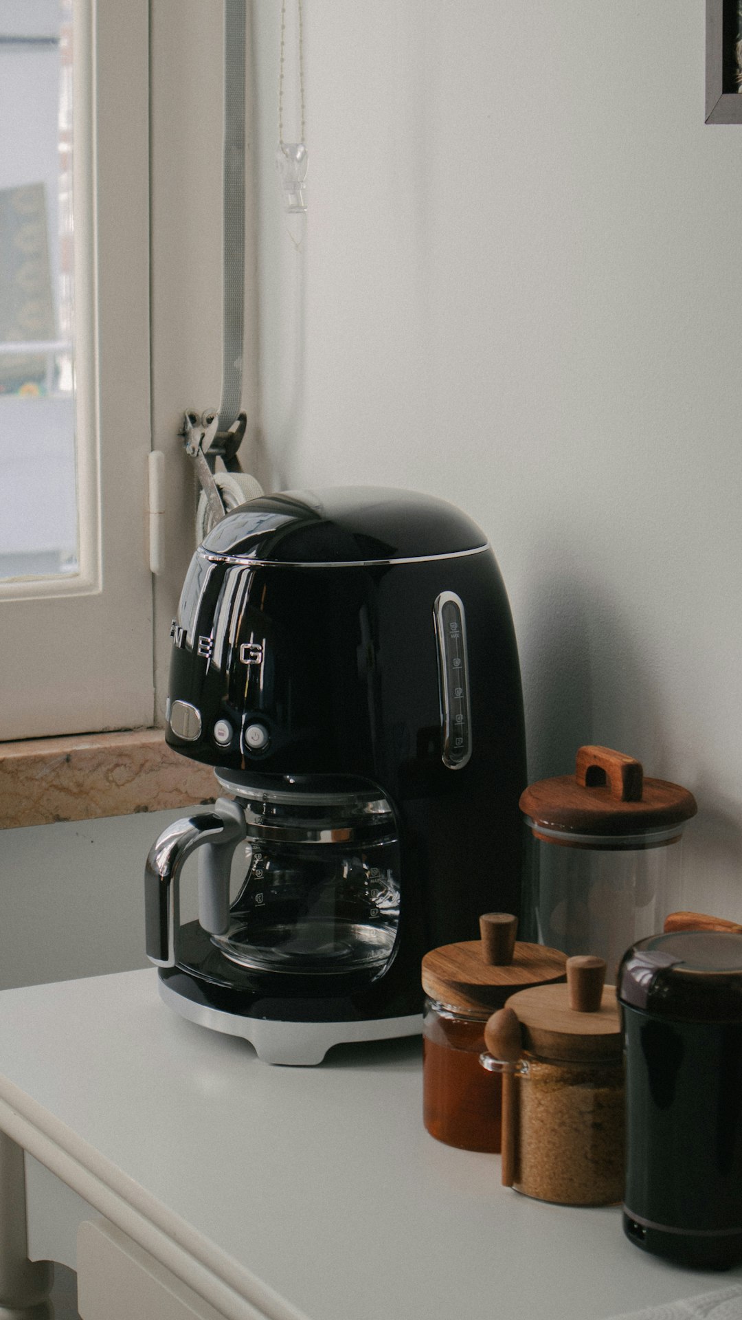 a black coffee maker sitting on top of a white counter