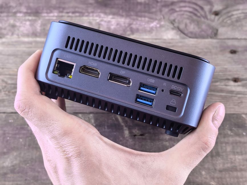 Close-up of a compact computer showing various ports held in a person's hand.