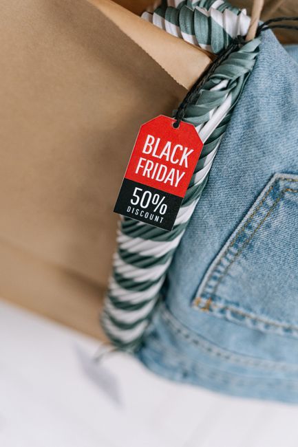 Close-up of a shopping bag with a Black Friday 50% discount tag and denim jeans visible.