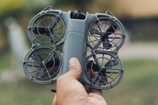 A compact controller-free drone held in one hand, similar to the DJI Neo