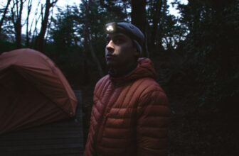 Man wearing a headlamp near a tent at night