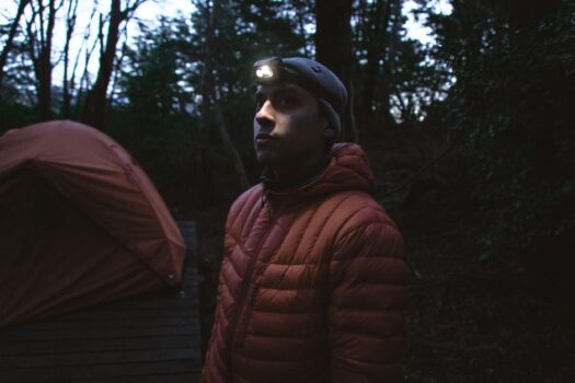 Man wearing a headlamp near a tent at night